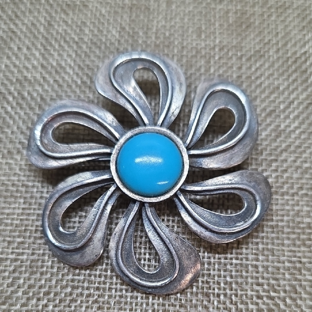 Sterling Silver flower brooch featuring a vibrant turquoise colored center